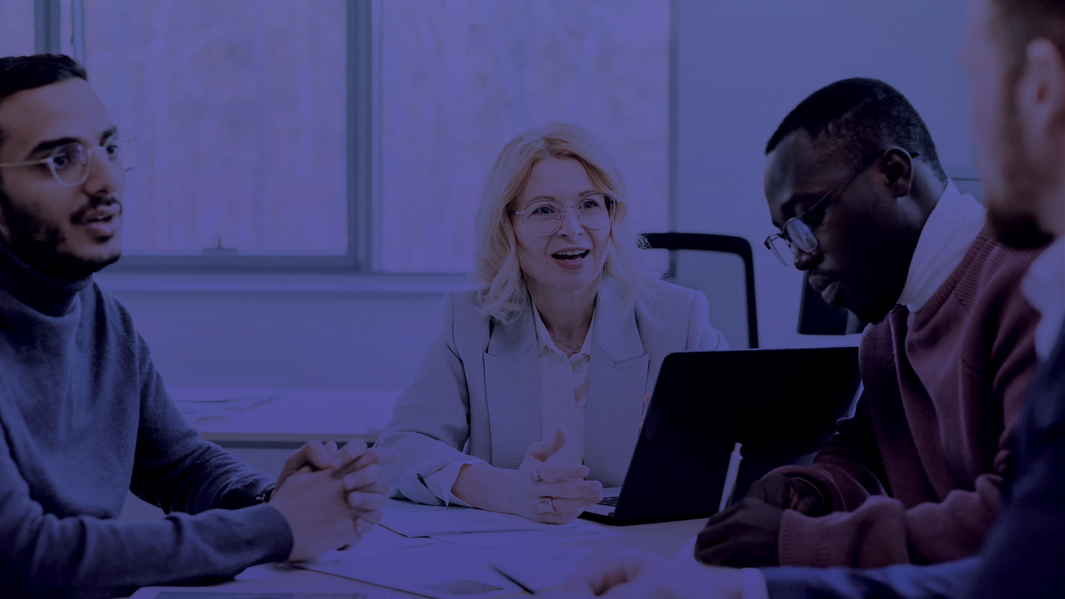 Four people at a table working with paper and laptop