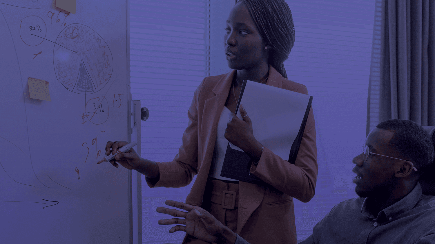 Two people looking at a whiteboard in an office with a pie chart
